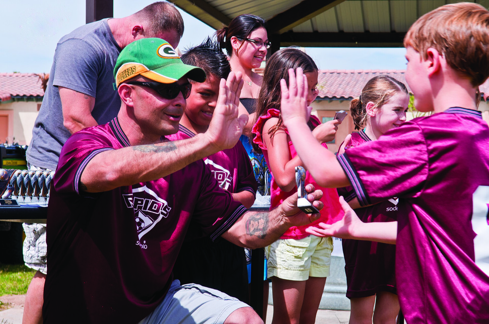 A dad high-fiving kids in soccer jerseys at an end-of-season team celebration