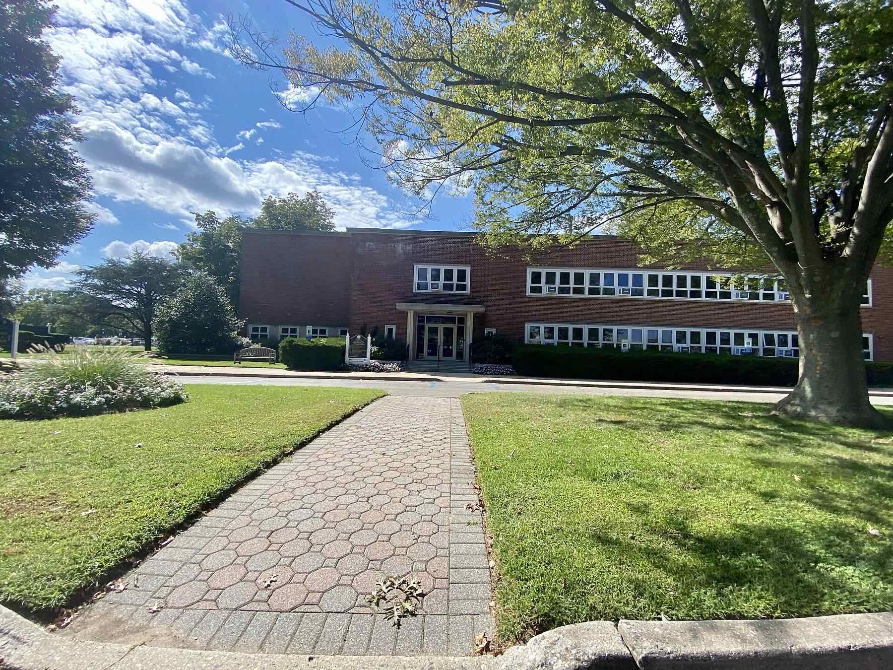 Garden City Village Hall, a two-storey brick building behind a lawn and a brick path